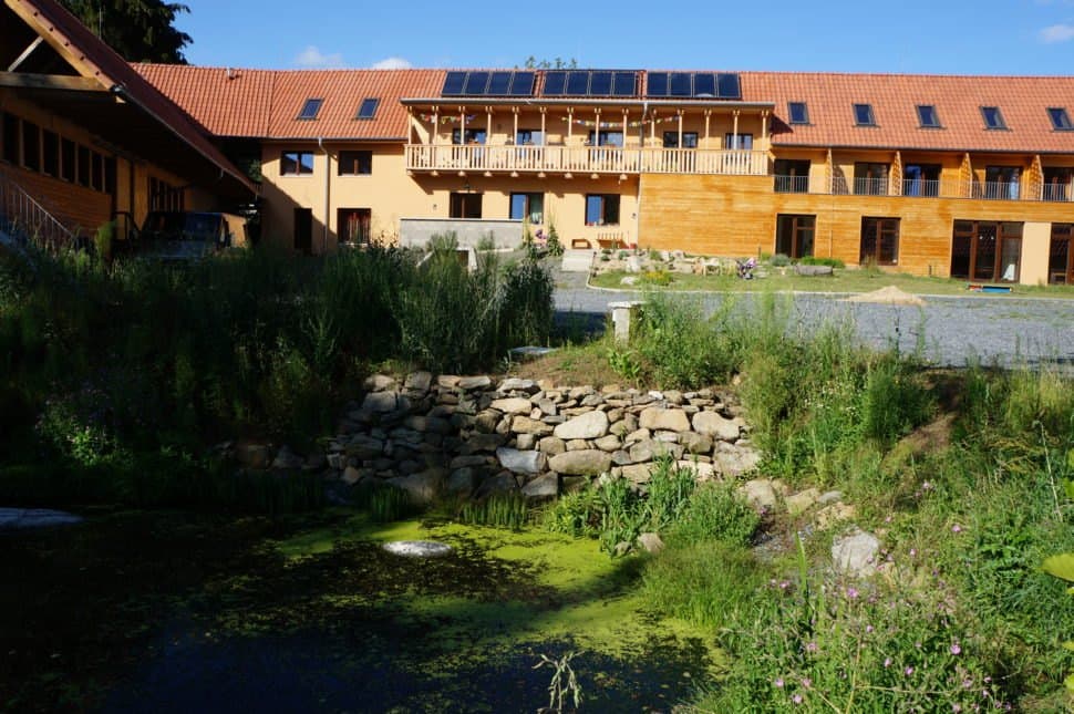 Ekocentrum Loutí – the main building with a natural pond in summer
