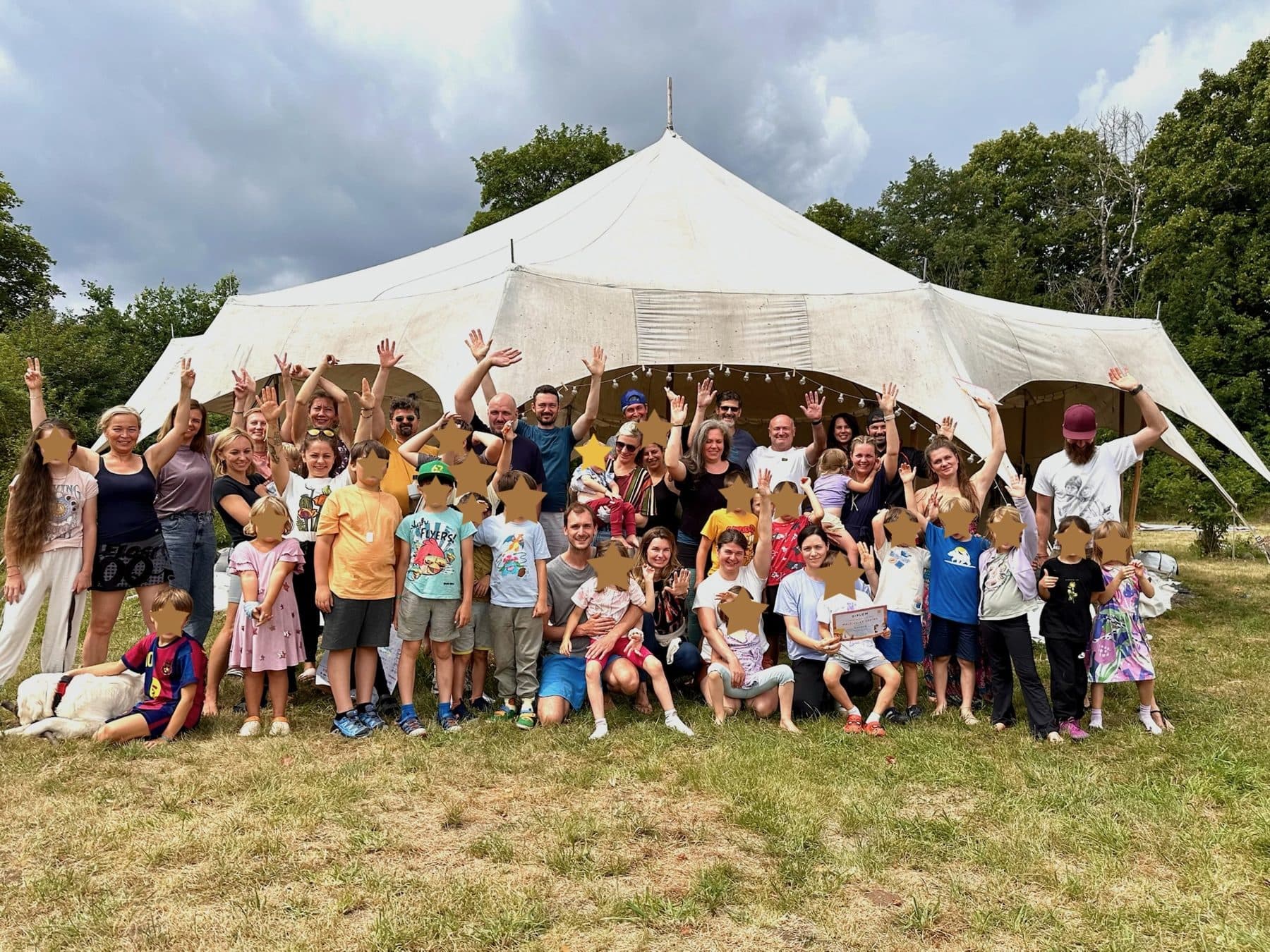 Group photo of parents, children and facilitators at our 2026 camp in front of the big tent